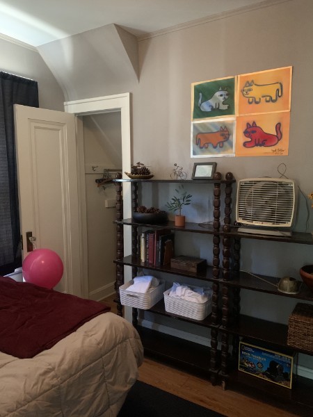 A cozy bedroom with storage shelves and colorful artwork